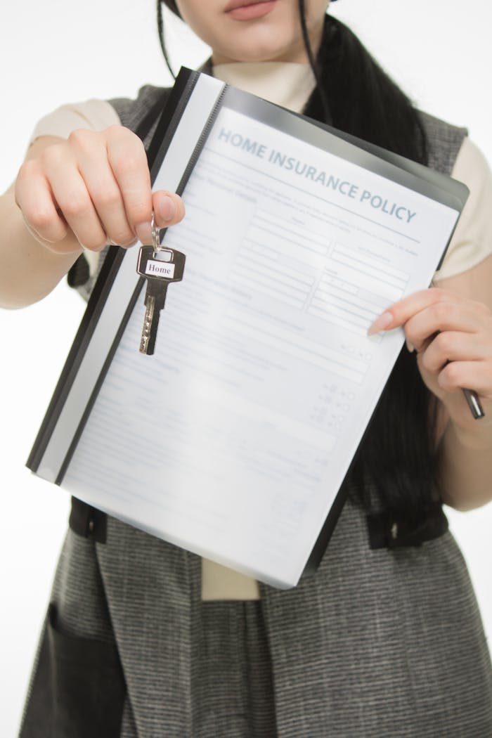 Services Close-up of person holding home insurance document and house key, symbolizing real estate and security.