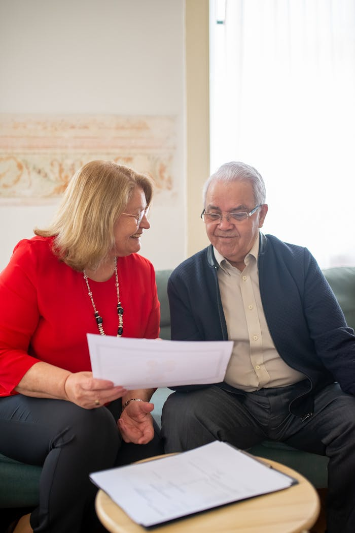 Services Senior couple consulting on pension options, smiling on a sofa, discussing documents.